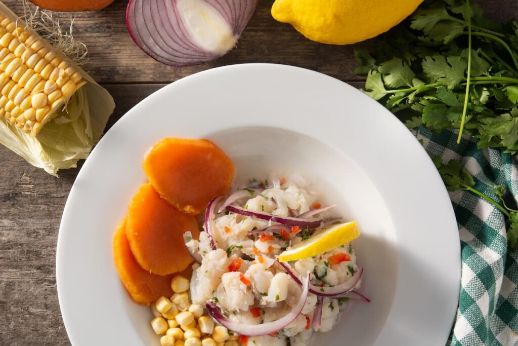 Imagem mostra Ceviche peruano tradicional com peixe, batata doce, milho e vegetais