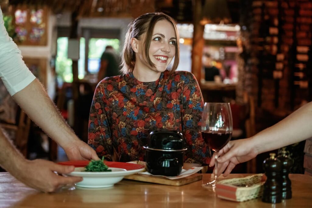 Imagem mostra mulher feliz sendo servida em um dos restaurantes em Gramado.