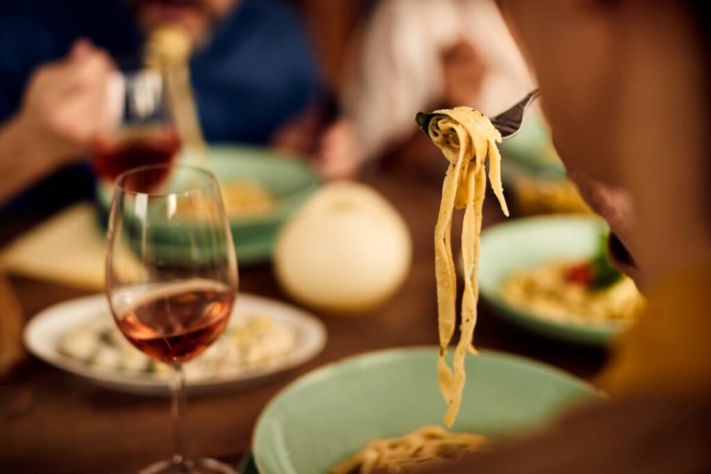 Imagem mostra comida italiana acompanhada de um bom vinho.