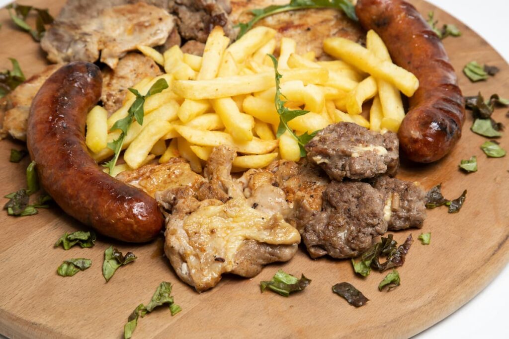 Imagem mostra tábua robusta com carne, linguiça e batata frita servida em um dos restaurantes na Bolívia.