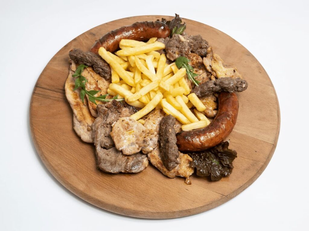 Imagem mostra tábua de carne com linguiça e fritas, encontrada em um doa melhores restaurantes na Bolívia.