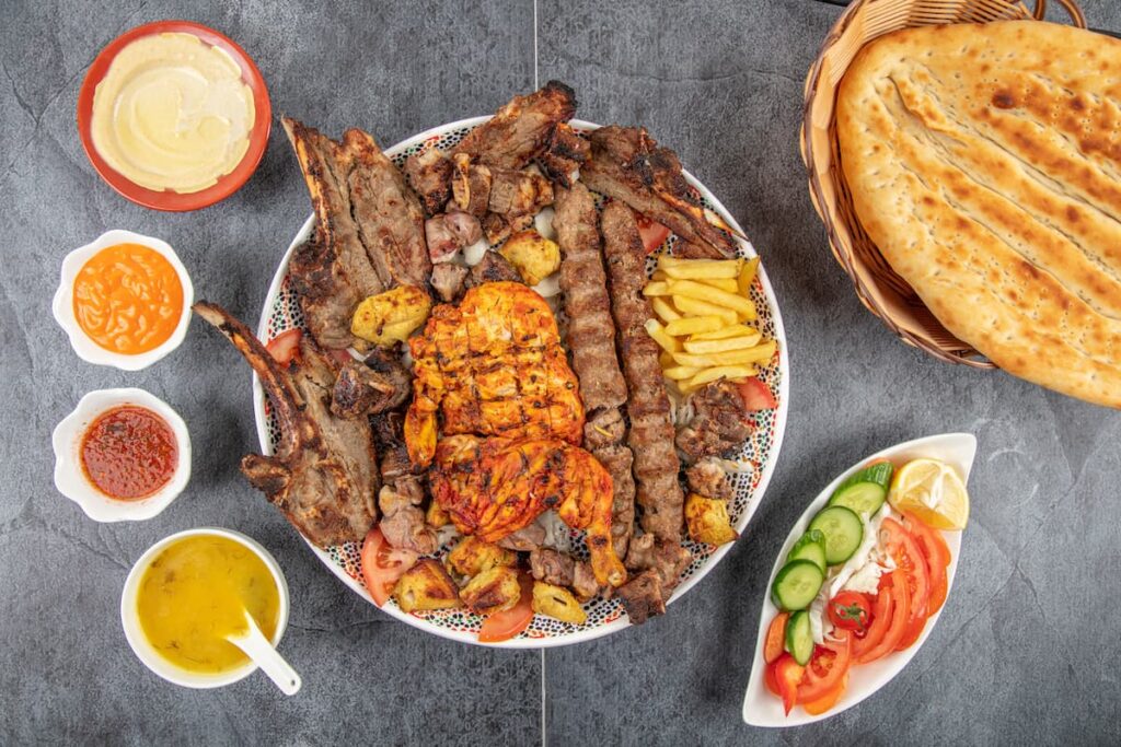 Imagem mostra comida libanesa diversa acompanhada de salada e molho.